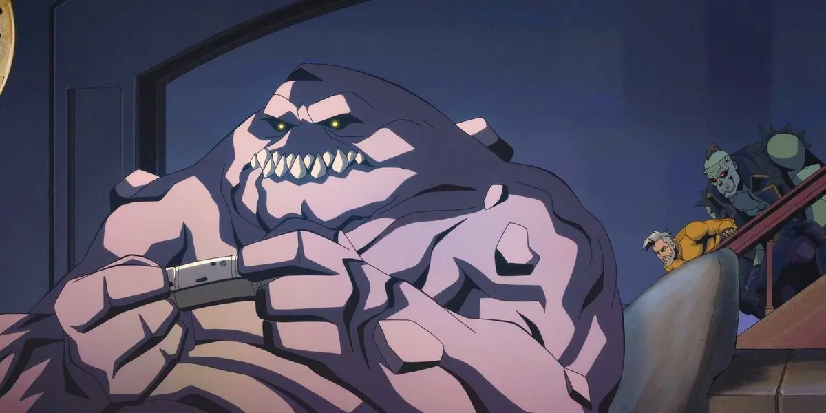 Clayface plays video games as Rick Flag and Frankenstein sneak down a set of stairs behind him from Creature Commandos