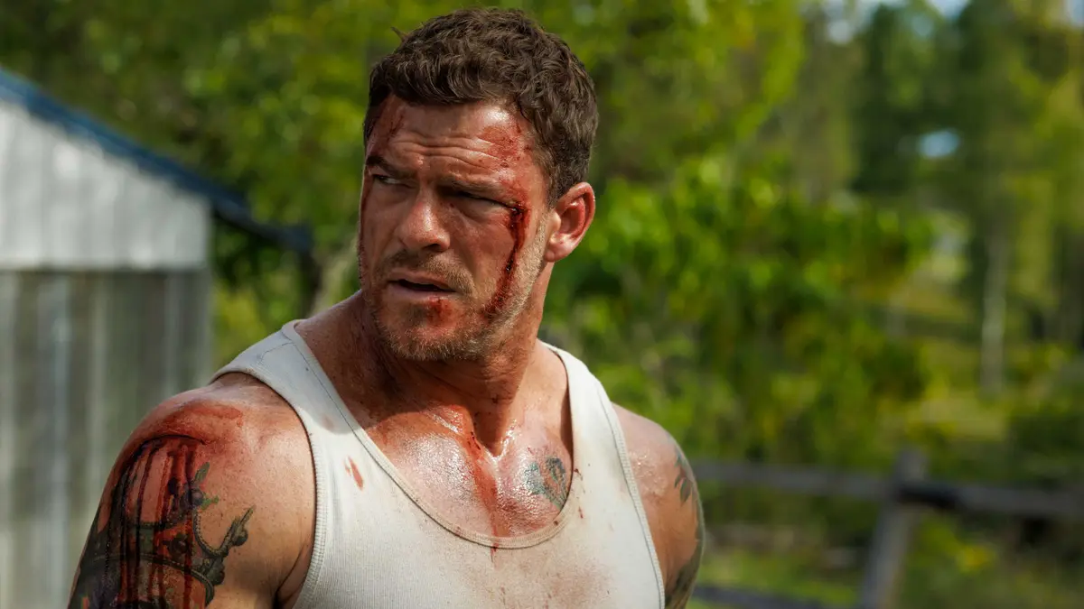 A bloodied Alan Ritchson looks over his shoulder in Runner