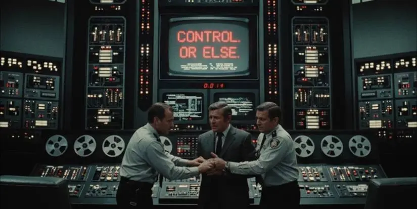 Three men standing in front of a machine that says "Control or Else" in 'Colossus: The Forbin Project'