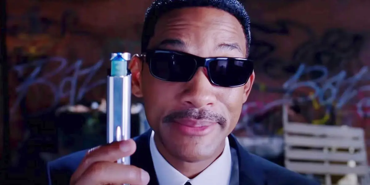 Agent J, played by Will Smith, wearing a black suit and holding a neuralyzer in Men in Black 3