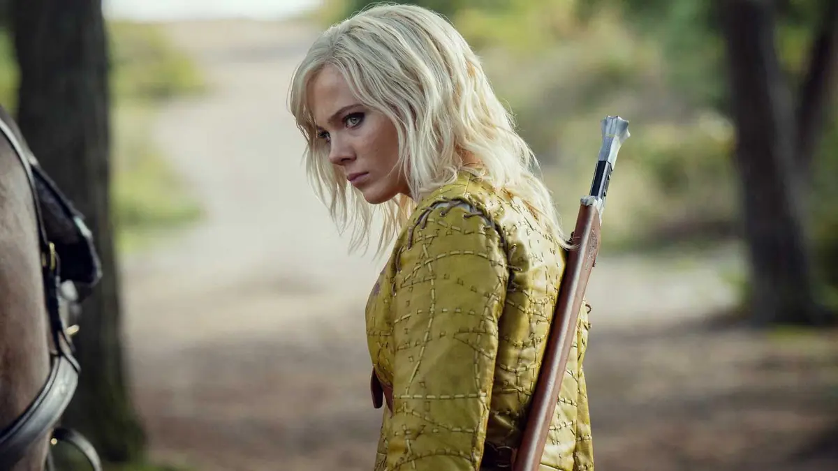 Ciri (Freya Allan) standing side on and glancing into the distance with a weapon on her back in The Witcher season 4