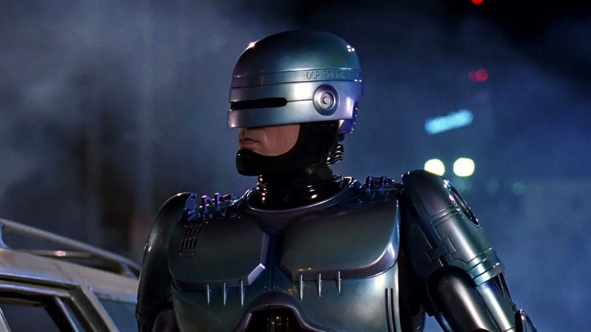 RoboCop standing outside at nighttime next to a car