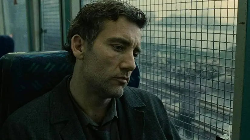 Theo Faron sits on a train as refugees can be seen through the window