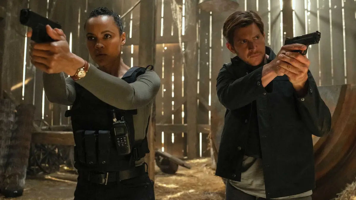 Neagley and Riley holding up guns in Neagley