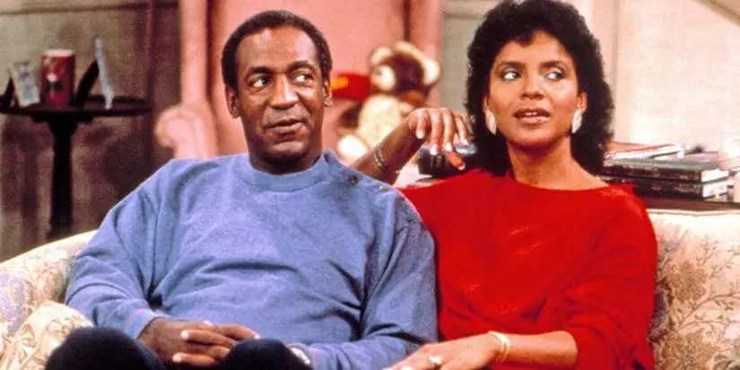 Cliff (Bill Cosby) and Clair Huxtable (Phylicia Rashad) sat on a couch together in The Cosby Show