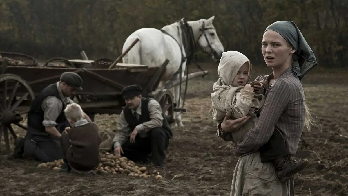 A woman holding a child in a field in Hatred (2016)