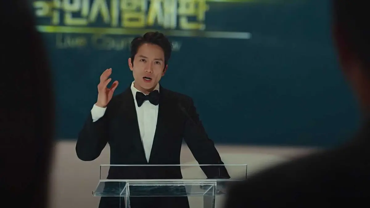 A Korean man in a suit stands at a glass podium