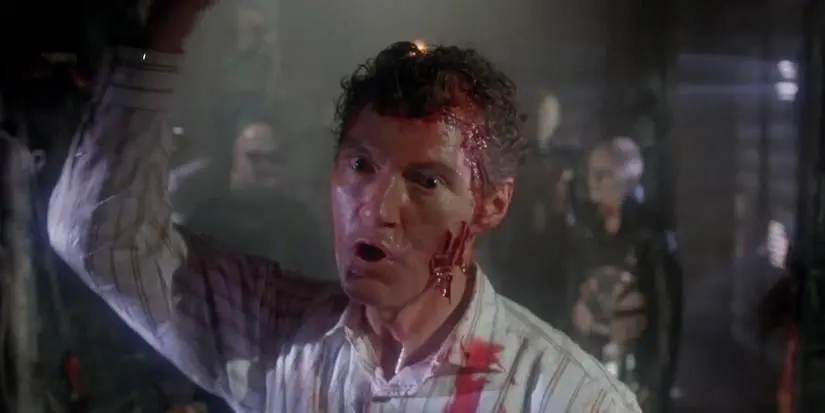 Frank with his hand raised and Cenobites standing behind in Hellraiser