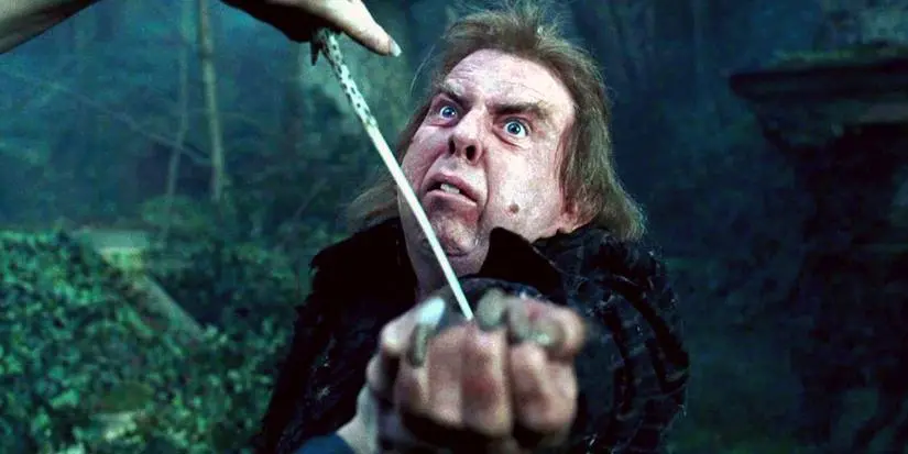 A frightened Peter Pettigrew with his arm extended before him as Voldemort casts a spell in Harry Potter