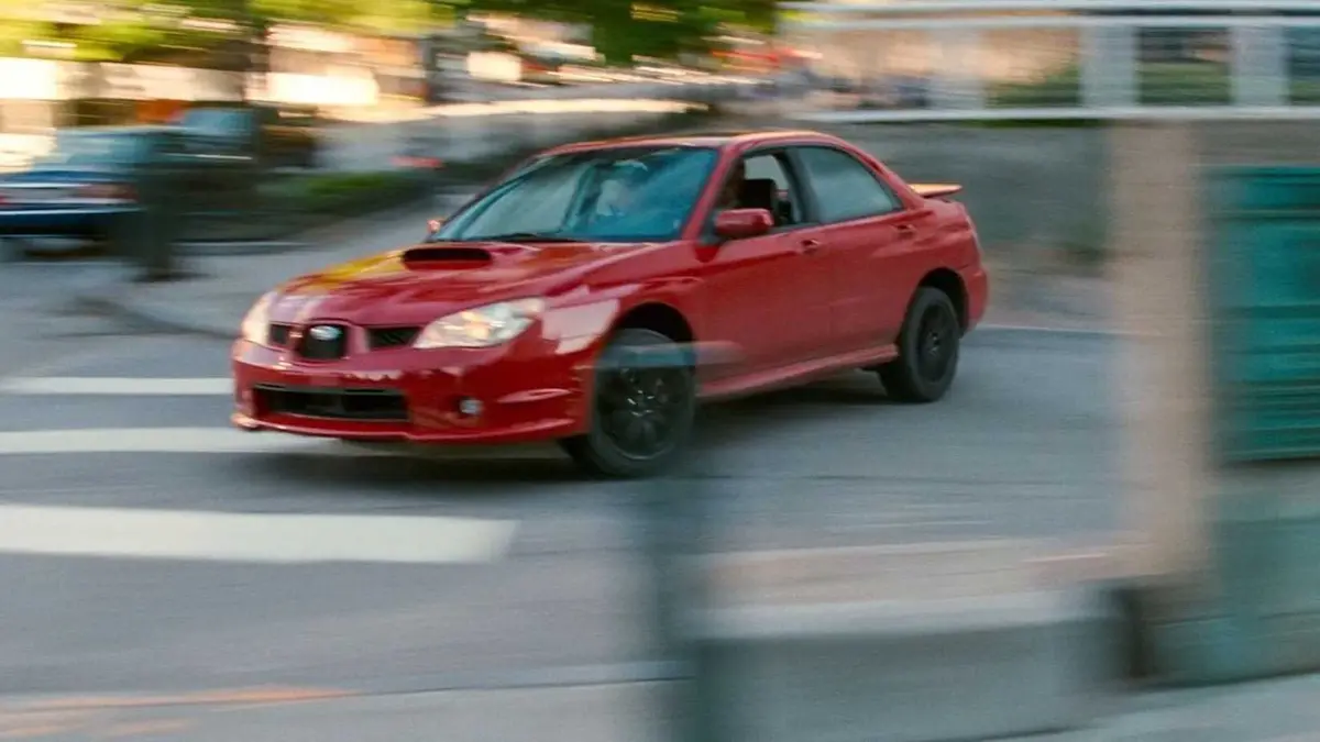 Baby sliding a red car into a highstreet in Baby Driver