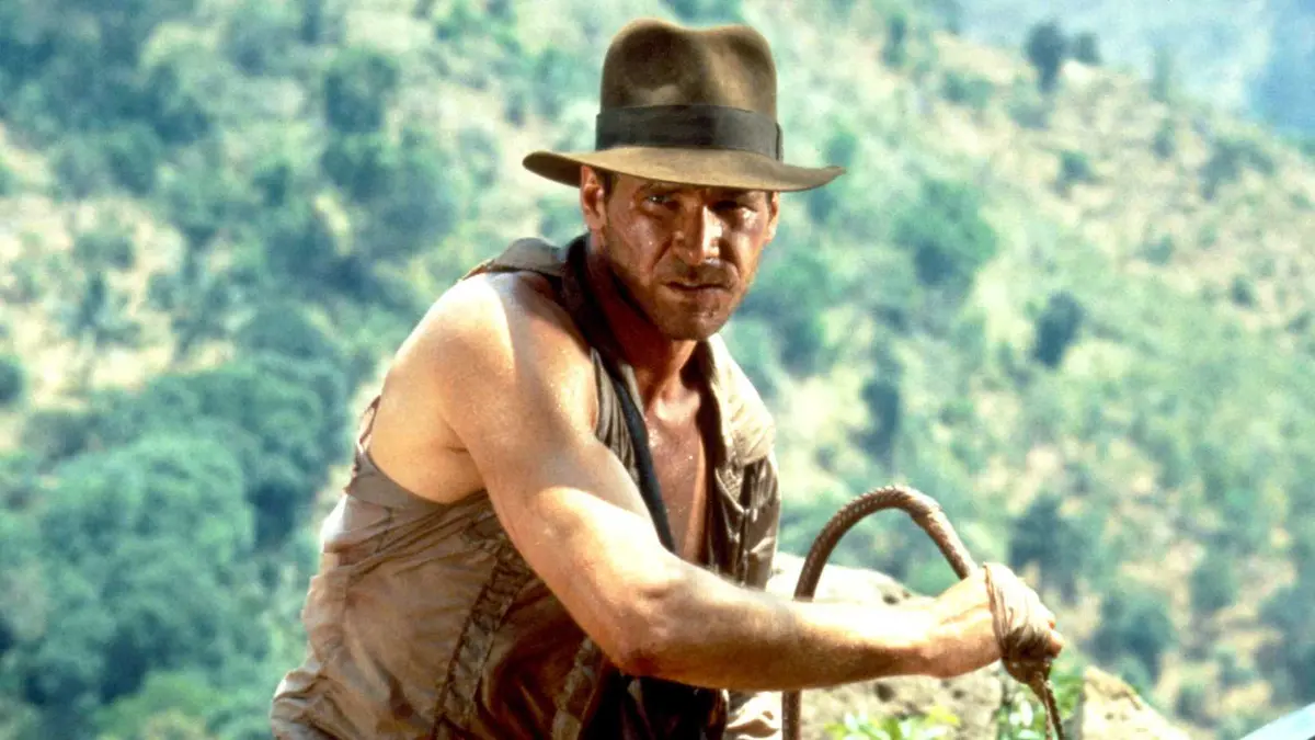 Harrison Ford as Indiana Jones holding his whip and wearing his hat in Indiana Jones and the Temple of Doom