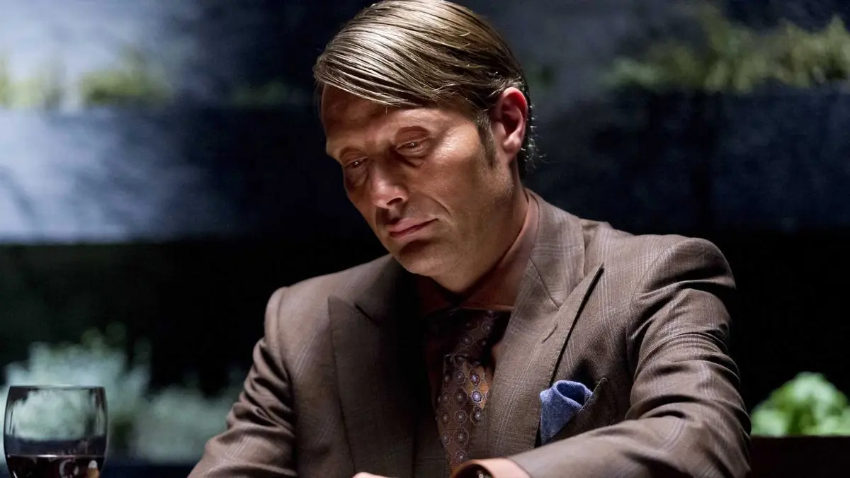 Mads Mikkelsen's Hannibal Lecter sits at a table in Hannibal