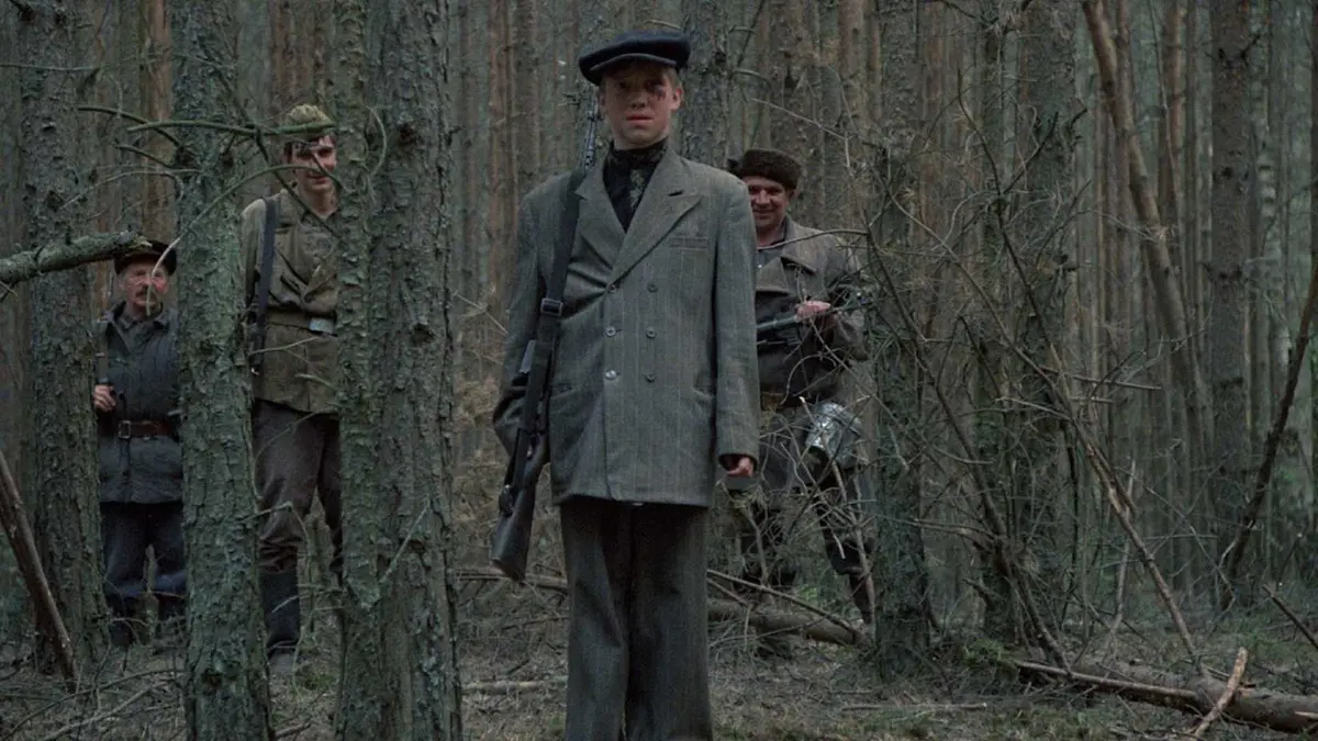 A young boy stands with other soldiers in the woods in Come and See
