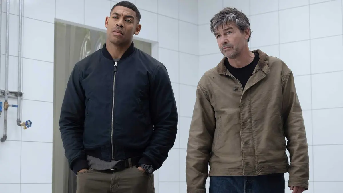 John Stewart (Aaron Pierre) and Hal Jordan (Kyle Chandler) standing in a slaughter factory in Lanterns season 1
