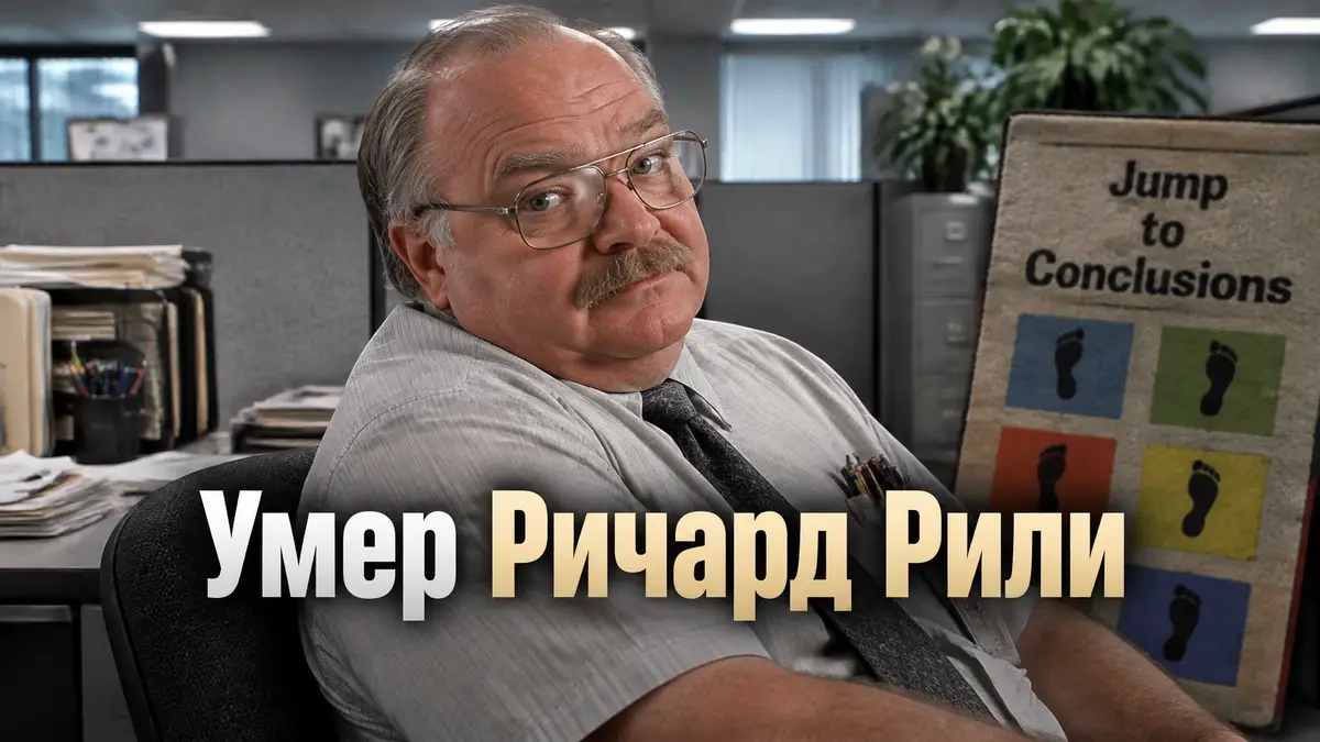 Ричард Рили в роли Тома Смыковски из «Офисного пространства» с усами, в офисе, рядом коврик Jump to Conclusions