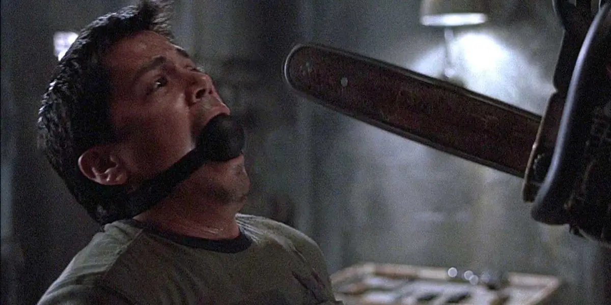 Jay Hernandez as Paxton Rodriguez frightened with a ball gag in his mouth while someone holds a chainsaw in front of him just offscreen in Hostel