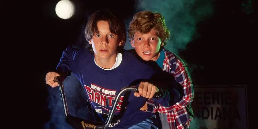 Two brothers ride a bike at night while looking scared in Eerie, Indiana