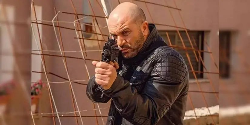 Lior Raz as Doron Kabilio pointing a gun in Fauda.
