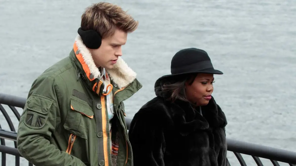 A young white man and a young Black woman bundled up in winter clothes walking down a street