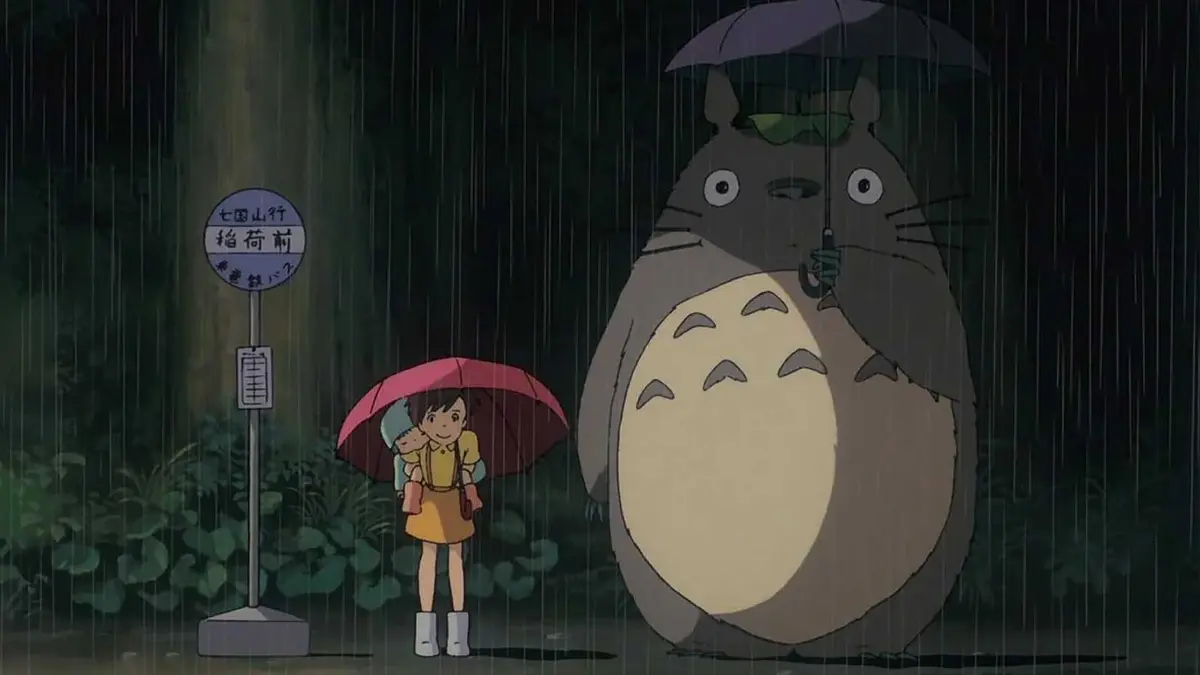 Mei and Satsuki stand next to Totoro in My Neighbor Totoro.