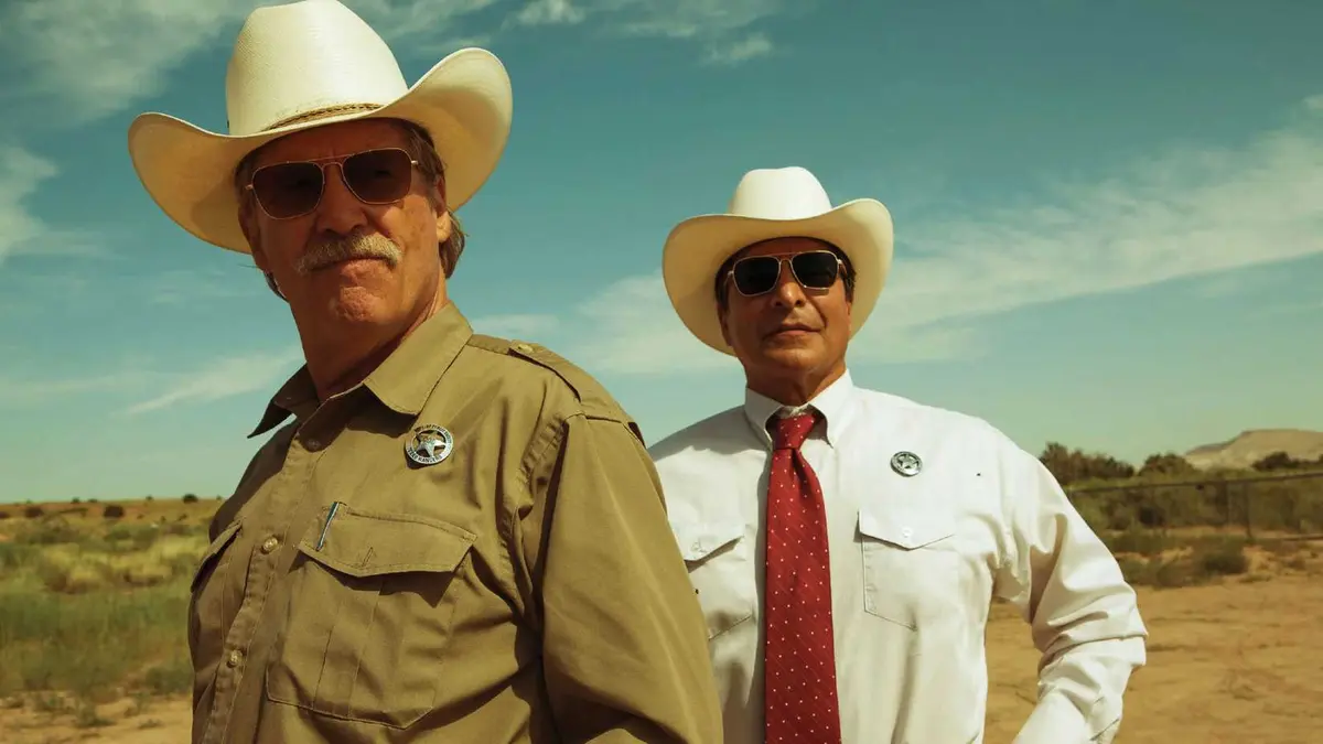 Jeff Bridges and Gil Birmingham as Texas Rangers stand in the desert wearing sunglasses and cowboy hats in Hell or High Water
