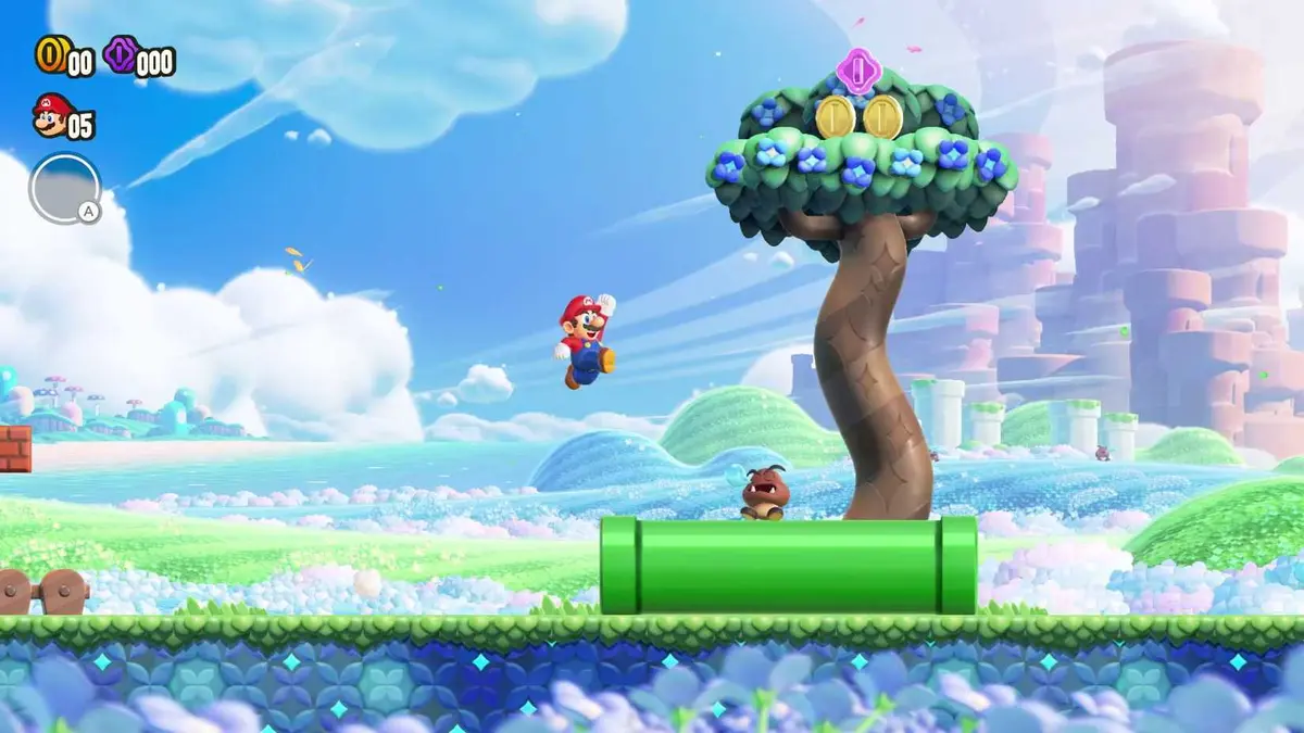 Mario leaps joyfully toward a Goomba sleeping on a pipe, in front of a fat tree, in Super Mario Bros. Wonder