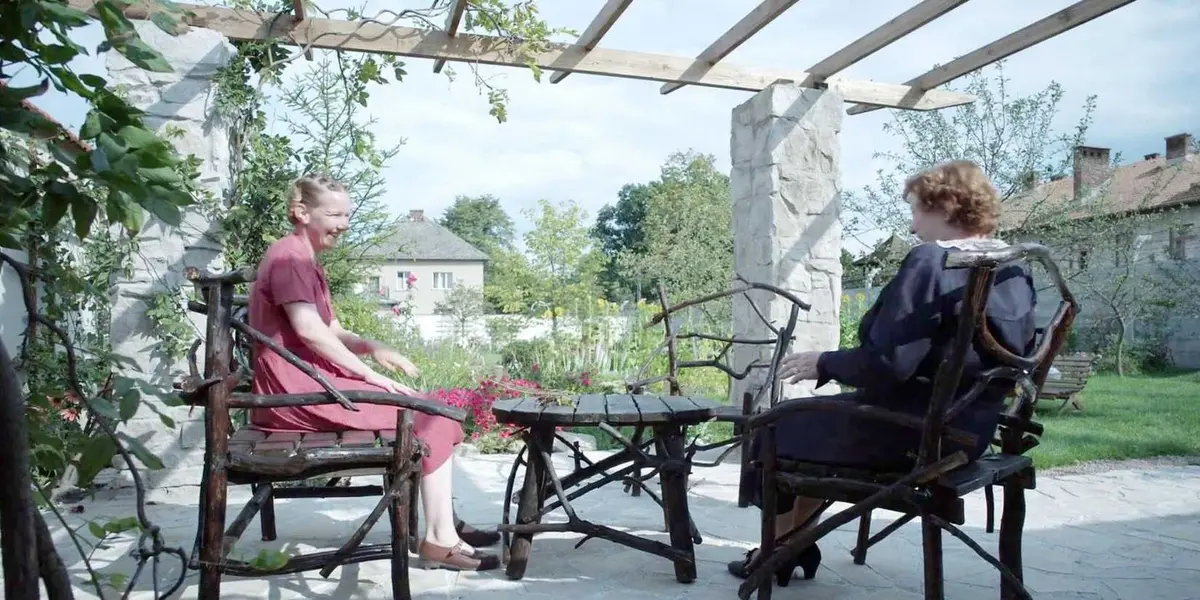 Hedwig (Sandra Huller) and her mother (Imogen Kogge) in the Zone of Interest seated in a garden