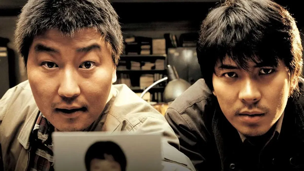 Song Kang-ho as Park Doo-man and Kim Sang-kyung as Seo Tae-yoon show a photo in Memories of Murder