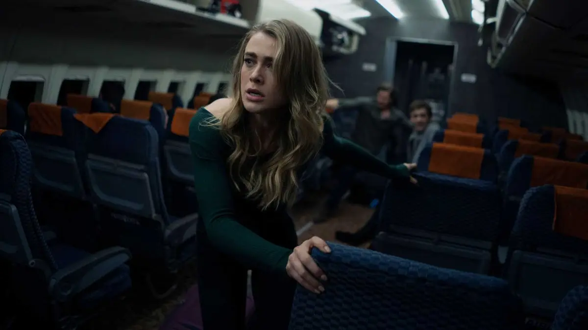 Melissa Roxburgh as Michaela Stone struggling to climb through a plane aisle in Manifest.
