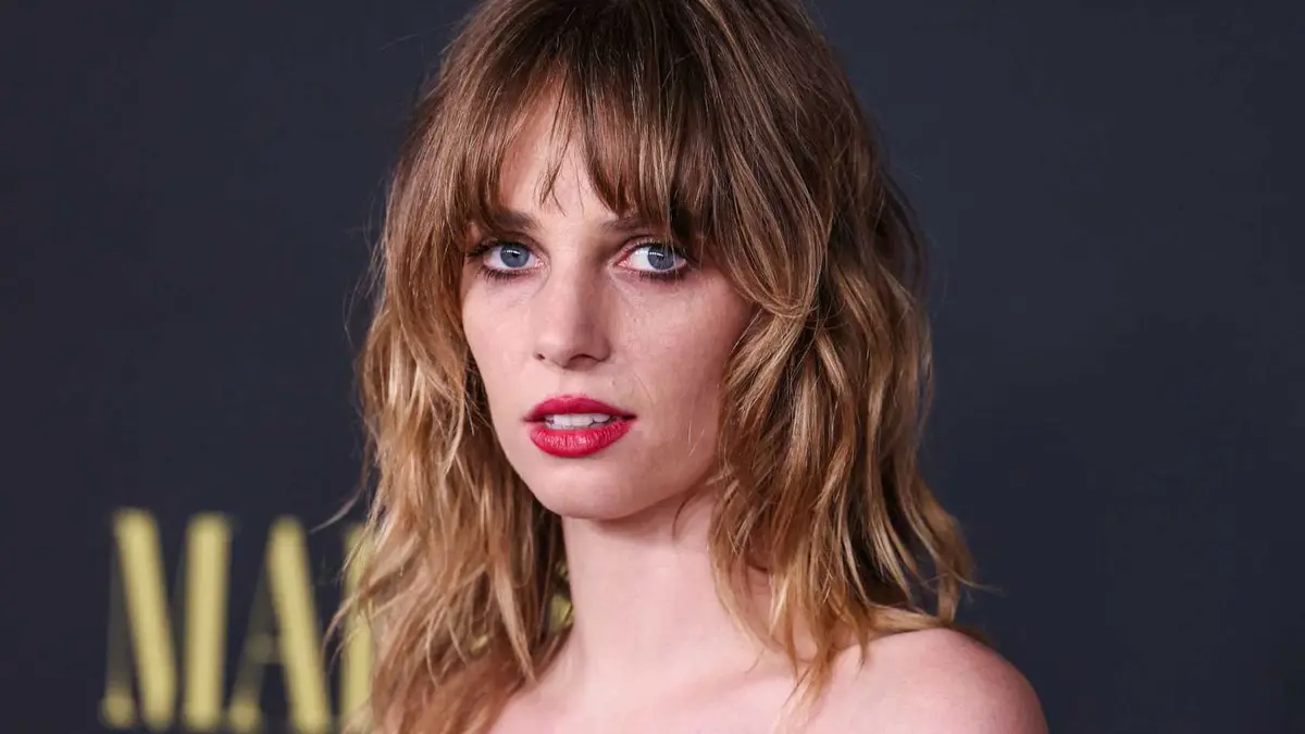 Maya Hawke looks forward with a neutral expression while attending a red carpet