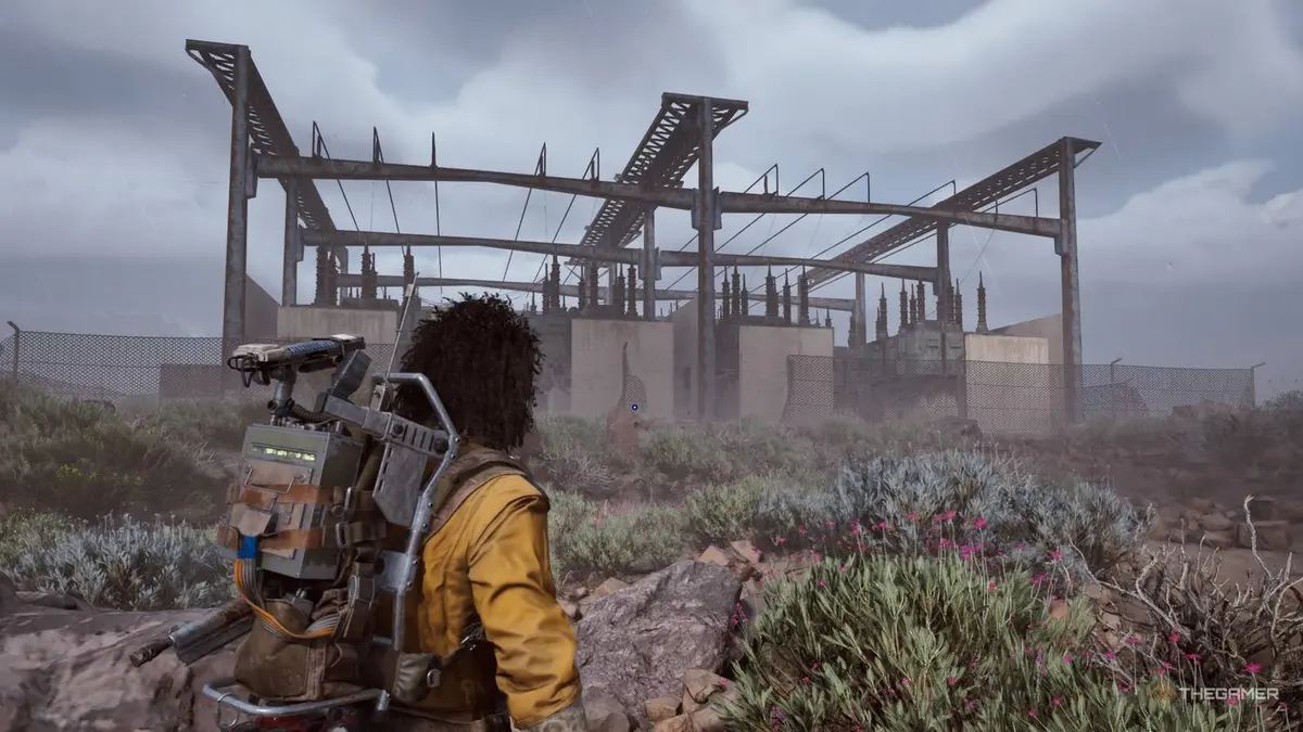Player raider approaching the electrical substation on Spaceport while it's raining in Arc Raiders.