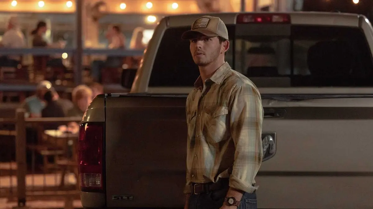Finn Little as Carter stands in front of a truck in Dutton Ranch Season 1