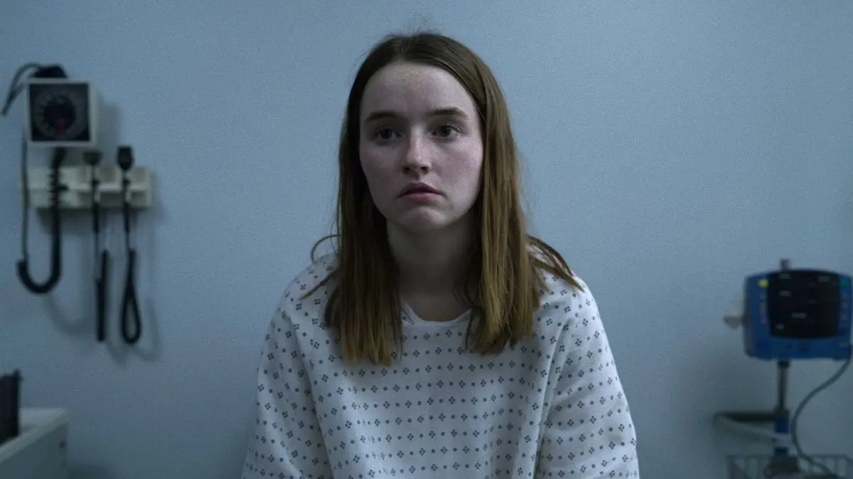 Kaitlyn Dever as Marie Adler sitting in a hospital room in a gown in Unbelievable.