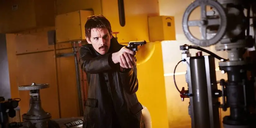 Ethan Hawke with his gun pointed at an unseen enemy in Predestination