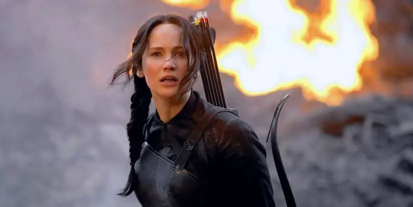 Katniss (Jennifer Lawrence) looking concerned as fire burns behind her in The Hunger Games: Mockingjay - Part 1