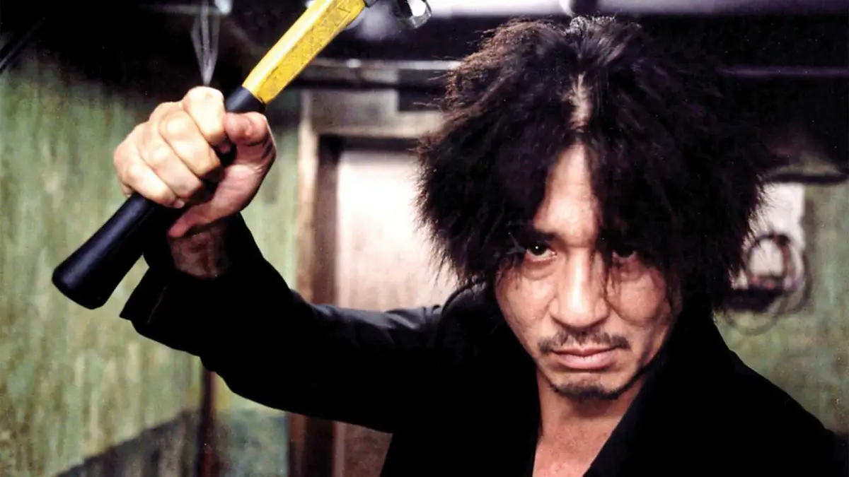 A man holds a hammer in the air in Oldboy
