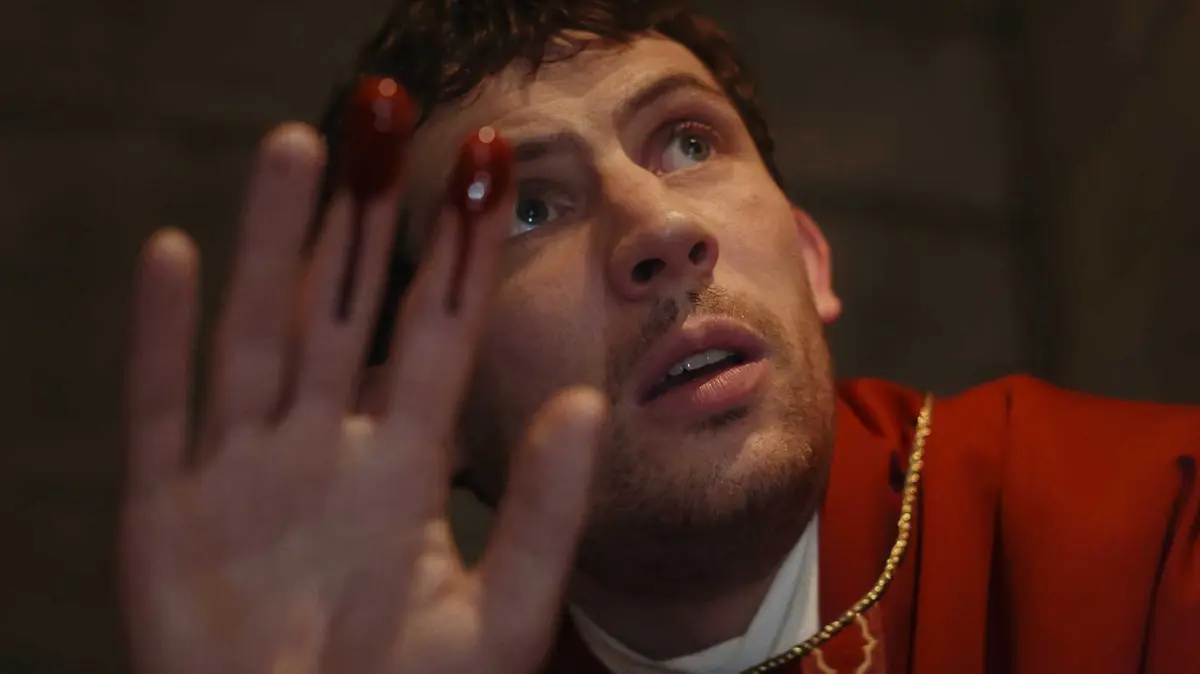 Father Jud Duplenticy (Josh O'Connor) with blood on his fingers in Wake Up Dead Man.