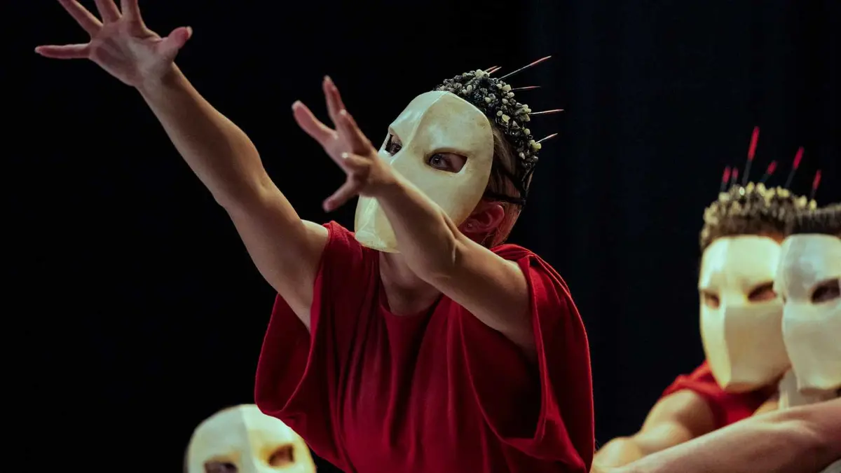 A still from episode 2 of Archive 81 on Netflix, an actor with a mask on their face wearing a red robe reaches into the air