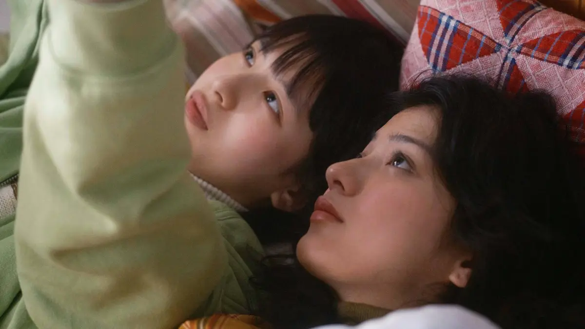 Two teens lying down next to each other and looking up at the same thing in Look Back