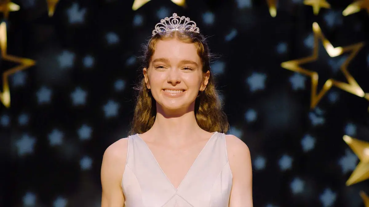 Carrie stands smiling in her prom dress in Carrie.