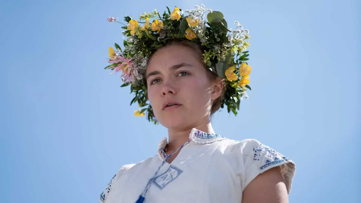 Florence Pugh as Dani wears a flower crown and looks down in Midsommar