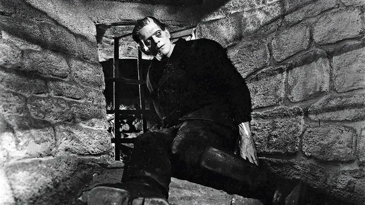 The Monster sits in a window in Frankenstein