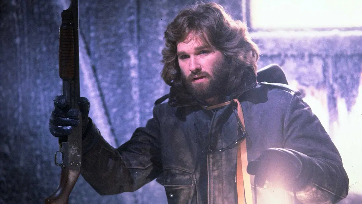Kurt Russell holding a shotgun and a lantern in The Thing