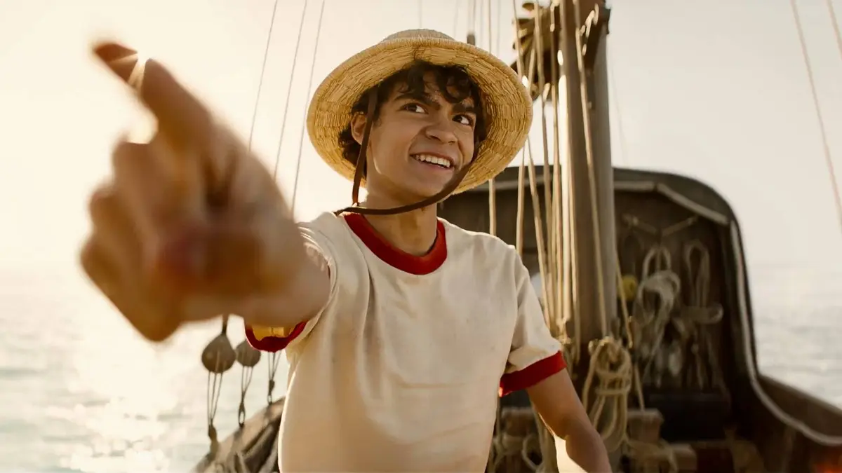 Iñaki Godoy as Monkey D. Luffy pointing his finger outward while atop the deck of a pirate ship in broad daylight in One Piece.