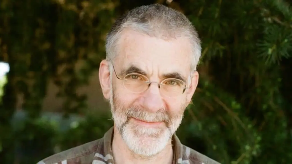 Man with glasses and grey hair smiling at camera