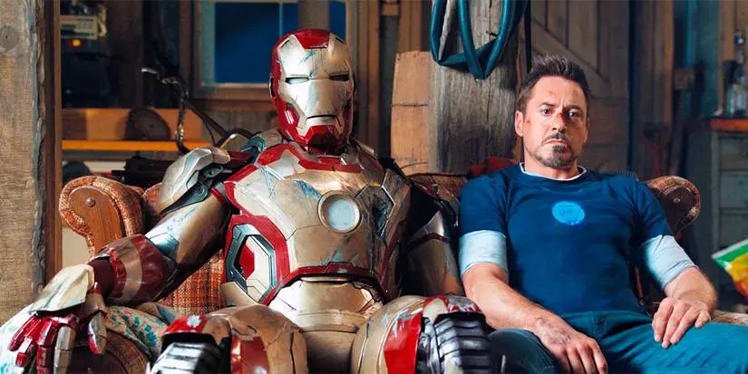 Tony Stark sits next to the Iron Man suit in Iron Man 3