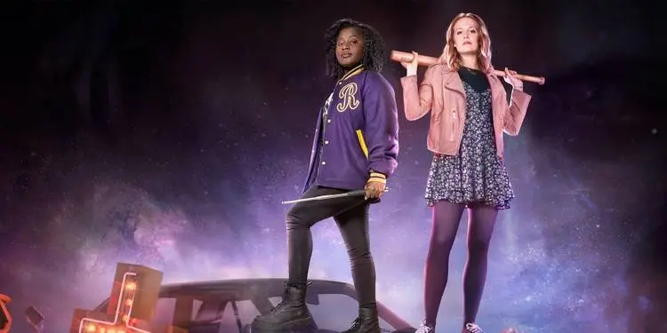 Susan Wokoma and Cara Theobold, standing on top of a car, holding weapons, in Crazyhead.