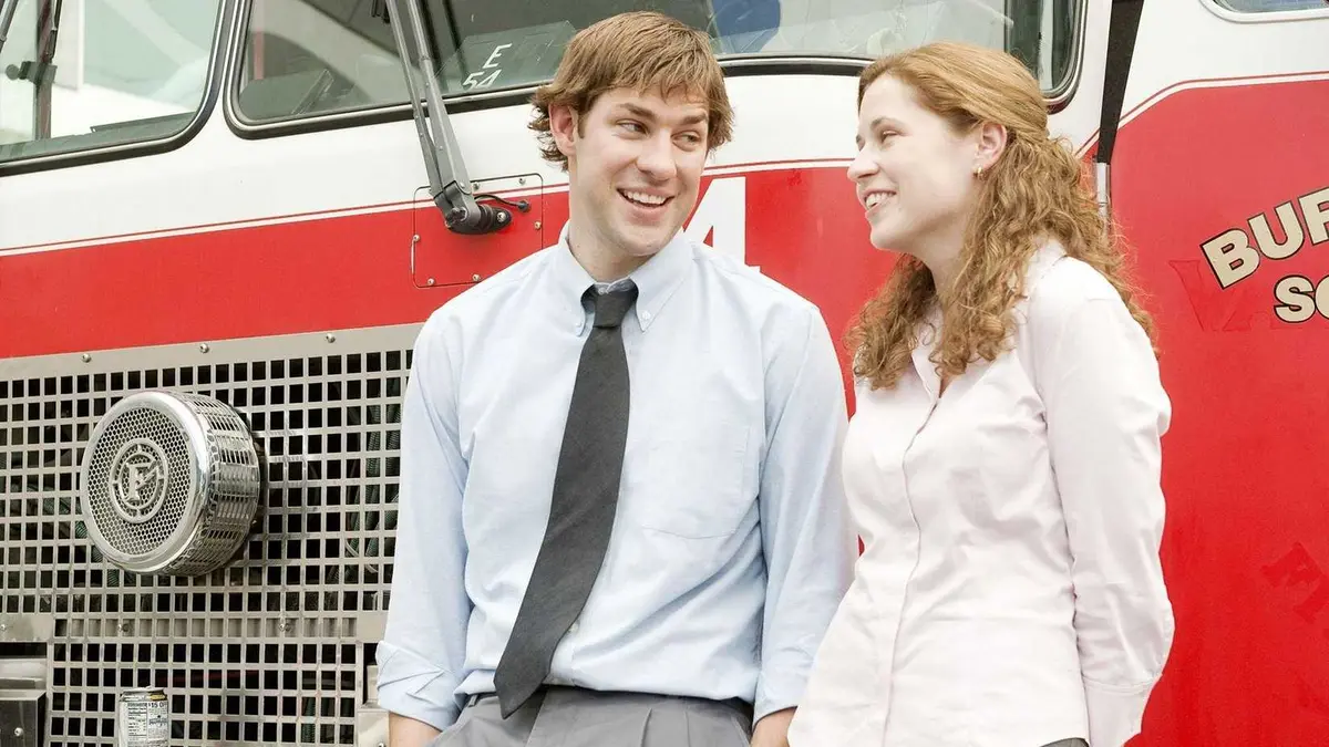 Jim (John Krasinski) laughing with Pam (Jenna Fischer) next to a fire truck in The Office.
